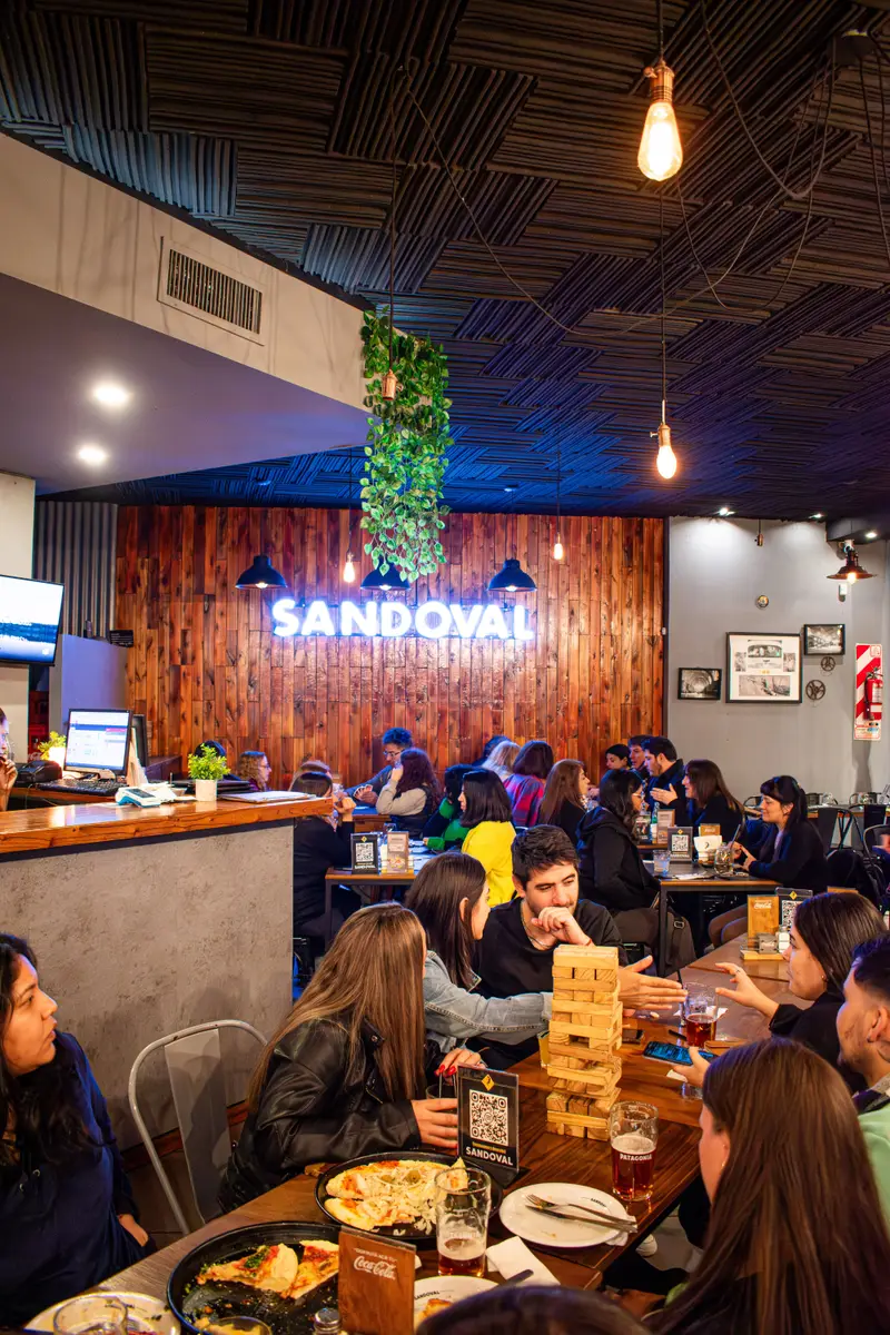 Salón lleno de Sandoval con mesas jugando juegos de mesa, Caballito